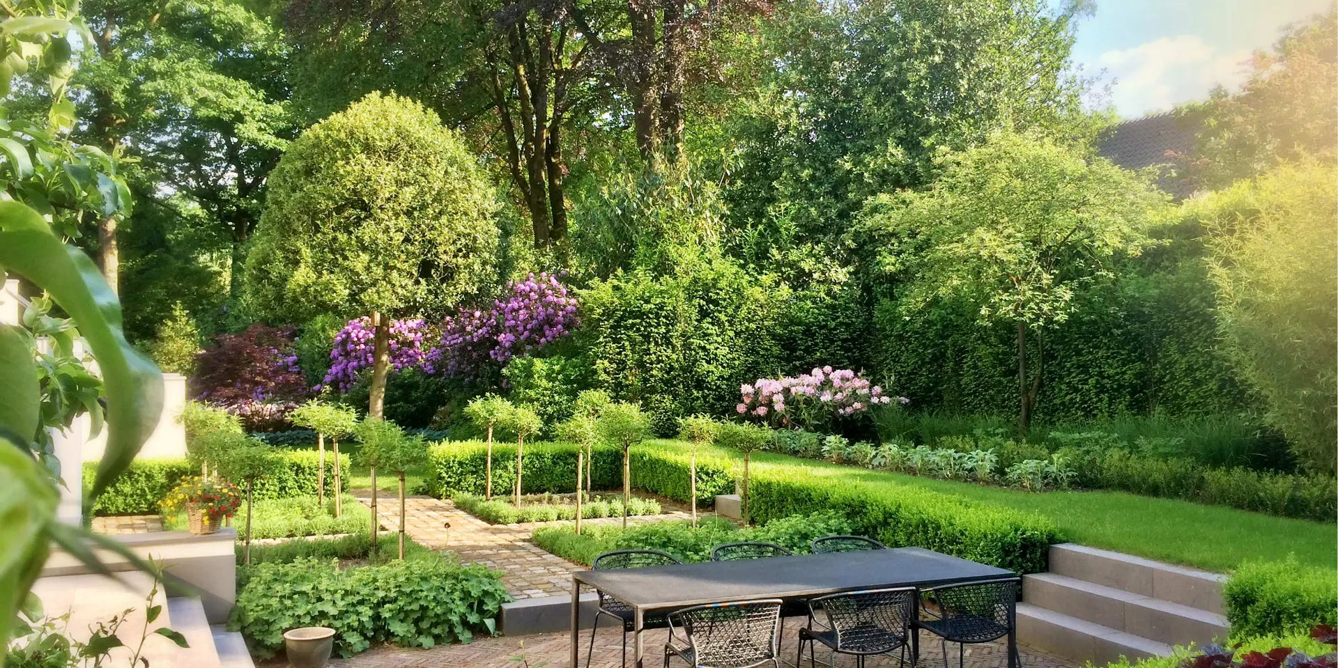 Weelderige tuin met natuurlijke beplanting, terras en zorgvuldig aangelegde tuinpaden